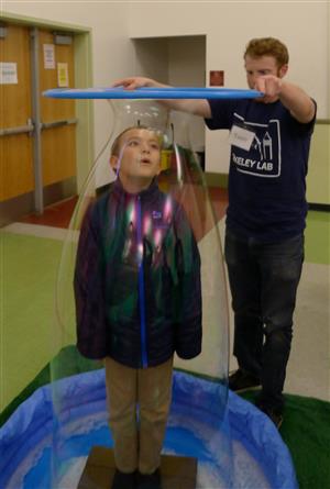 Teacher and student creating human-sized bubbles 